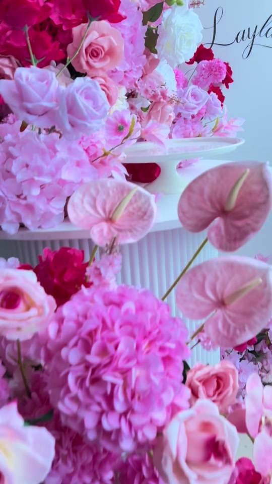 Pink anthuriums, hydrangeas and roses styled around a white cake table